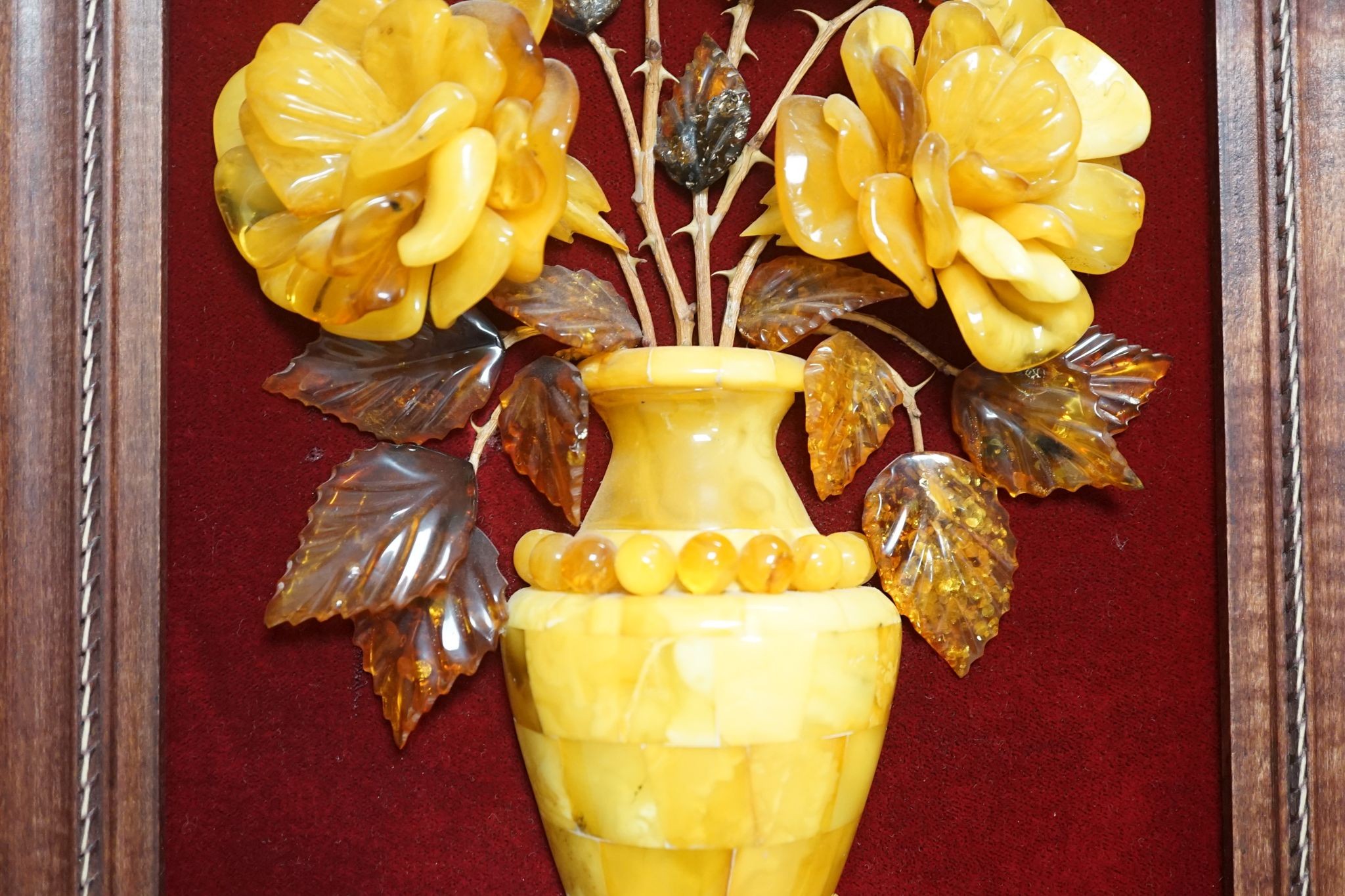 A carved amber panel from the Hermitage Museum shop, St Petersburg, roses in a vase. 49x39cm including frame
